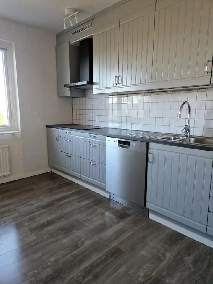Städat kök med rena bänkytor, diskbänk och diskmaskin